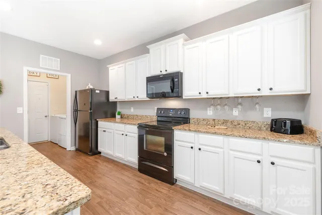 a kitchen with stainless steel appliances granite countertop a stove top oven a refrigerator and white cabinets