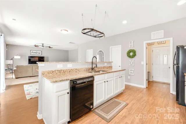 a large kitchen with stainless steel appliances granite countertop a lot of counter space and wooden floor
