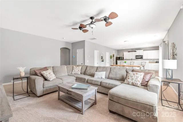 a living room with furniture kitchen view and a chandelier