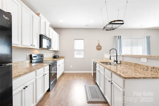 a kitchen with granite countertop a sink stove and cabinets