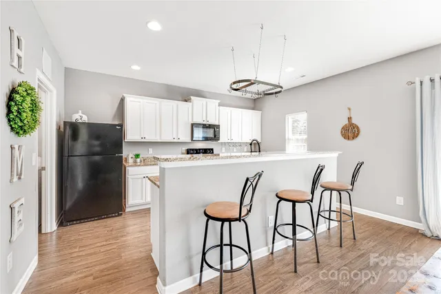 a kitchen with stainless steel appliances a dining table chairs refrigerator and microwave