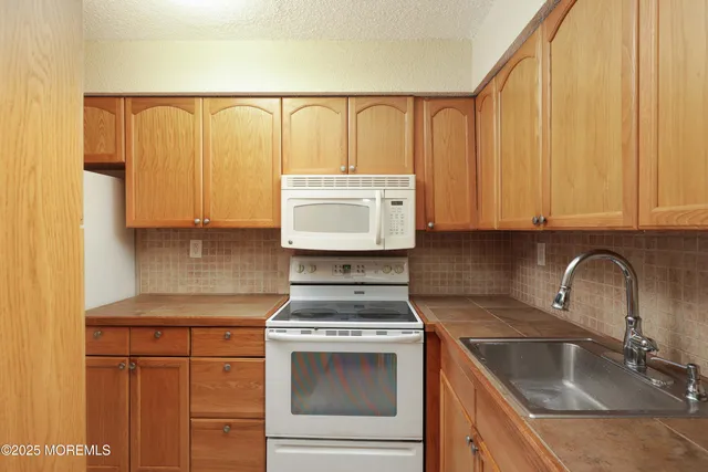 a kitchen with granite countertop a sink a stove and cabinets
