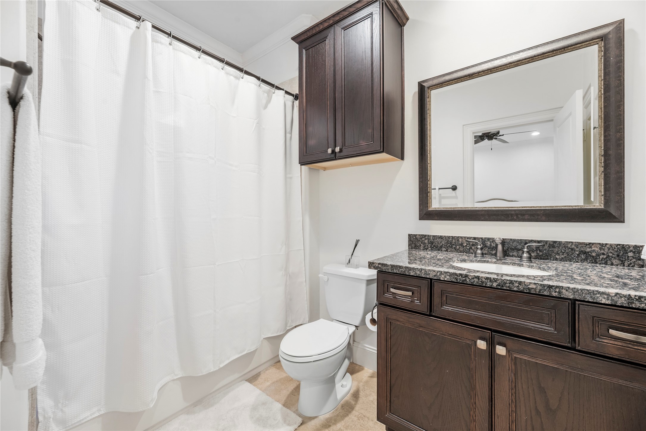 1537 Haddon Street Houston, TX 77006 - Photo 27 of 48 Third bathroom for the first floor bedroom (en-suite) features a modern design with dark wood cabinetry, a granite countertop, and a large framed mirror. It includes a bathtub with shower, offering a clean and elegant look.