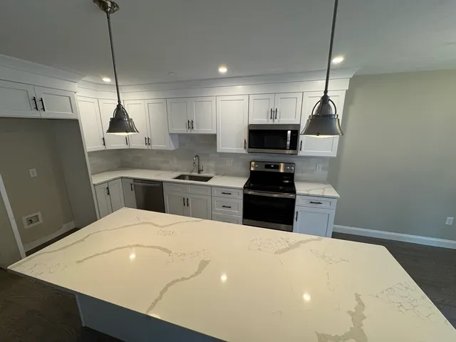 a kitchen with stainless steel appliances a stove a refrigerator a sink and white cabinets