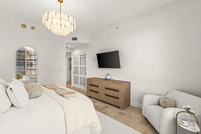 a spacious bedroom with a bed a couch and a chandelier