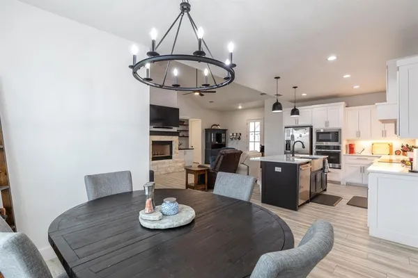 a kitchen with stainless steel appliances granite countertop a stove a kitchen island a dining table and chairs with wooden floor