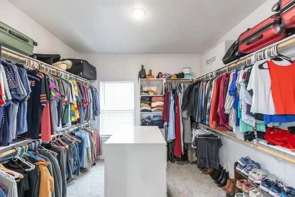 a view of walk in closet with clothes and shoes