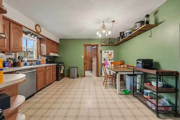 a open kitchen with stainless steel appliances kitchen island granite countertop a table chairs in it and a wooden floor