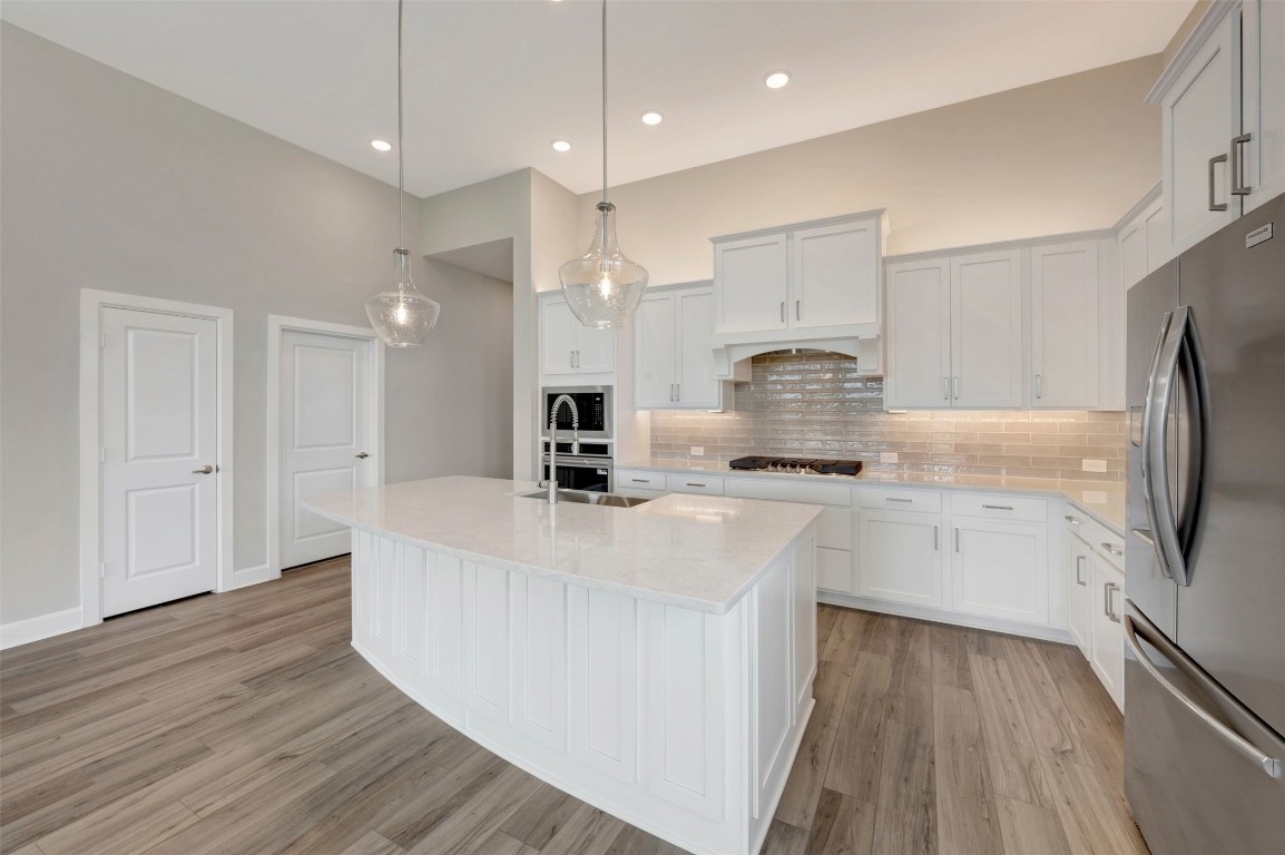 2423 Msn Hts Way Manvel, TX 77578 - Photo 28 of 49 a kitchen with kitchen island white cabinets and stainless steel appliances