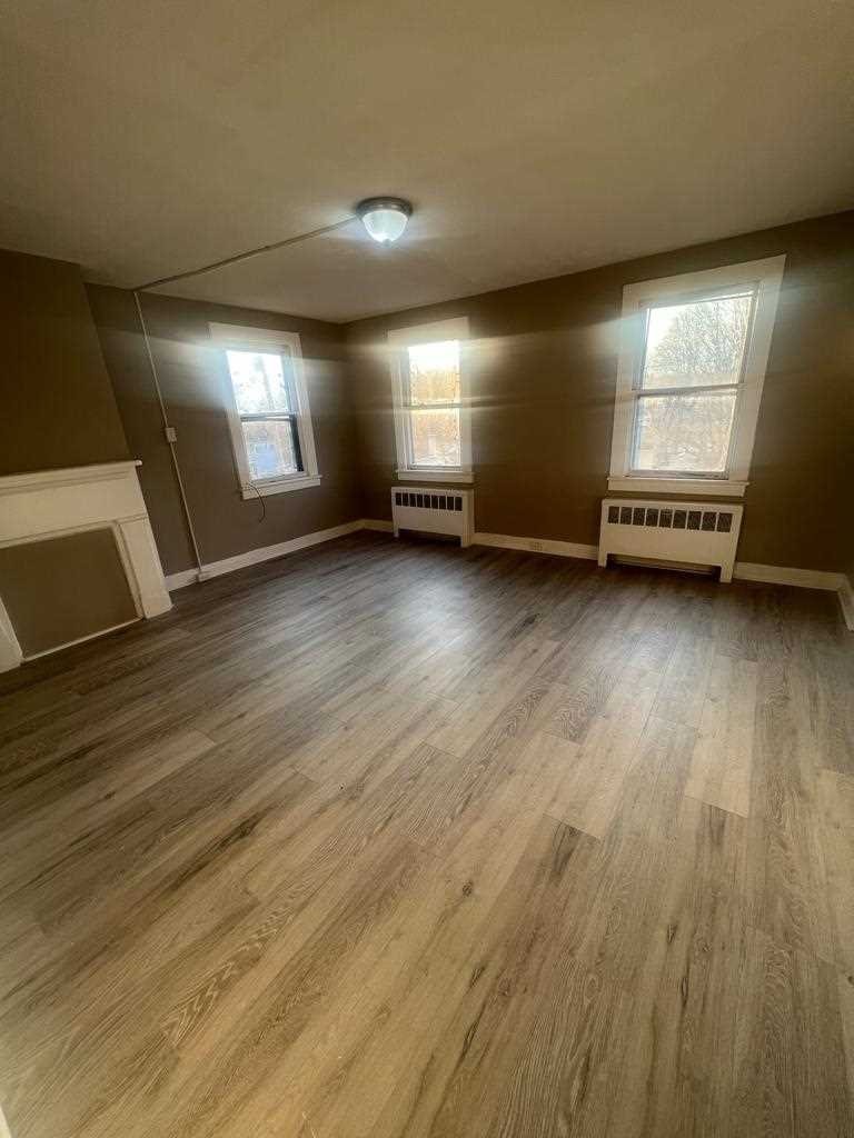 24-26 Spring Street, Unit 2 Wappingers Falls, NY 12590 - Photo 5 of 7 an empty room with wooden floor and windows