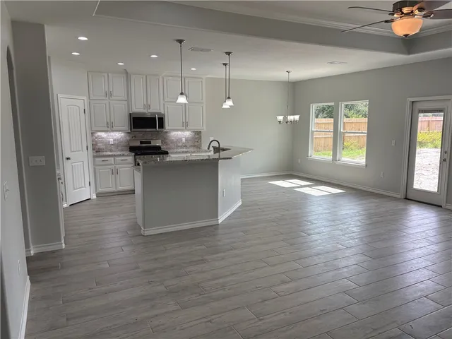 a kitchen with stainless steel appliances granite countertop a sink a stove and a wooden floors