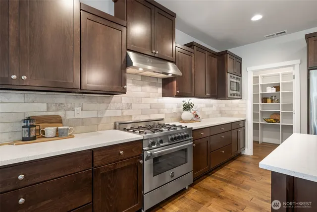 a kitchen with stainless steel appliances granite countertop wooden cabinets stove top oven and sink