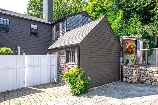 a view of brick house with small yard plants and wooden fence