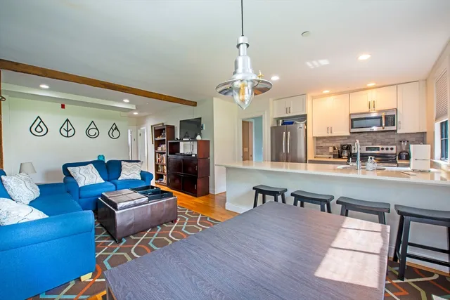 a living room with furniture kitchen view and a chandelier