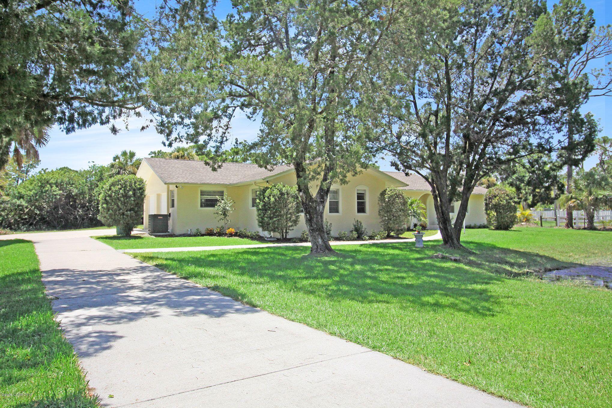 4521 Mustang Road Melbourne, FL 32934 - Photo 1 of 24 a front view of a house with a garden and trees