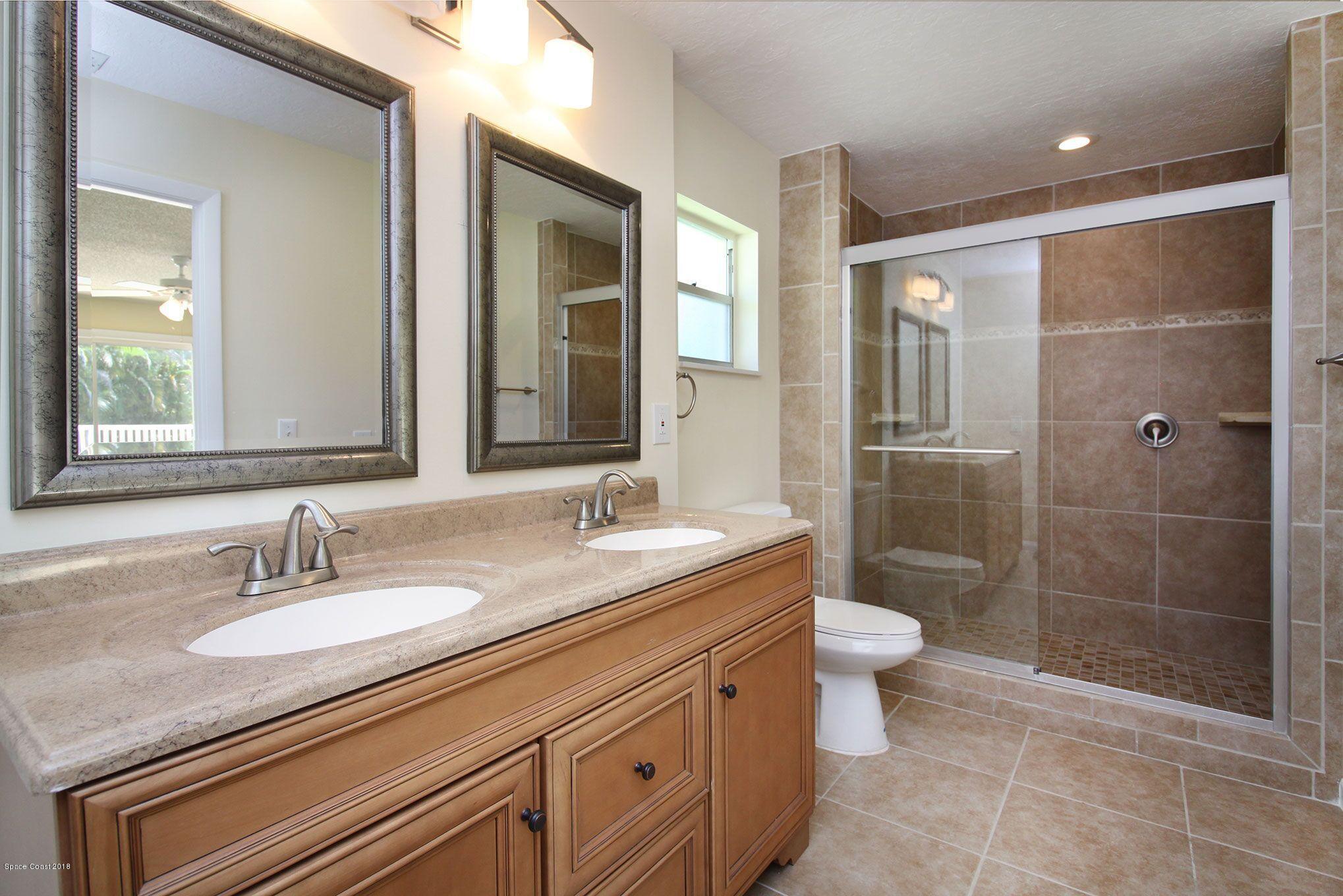 4521 Mustang Road Melbourne, FL 32934 - Photo 17 of 24 a bathroom with a granite countertop sink a toilet a mirror and shower