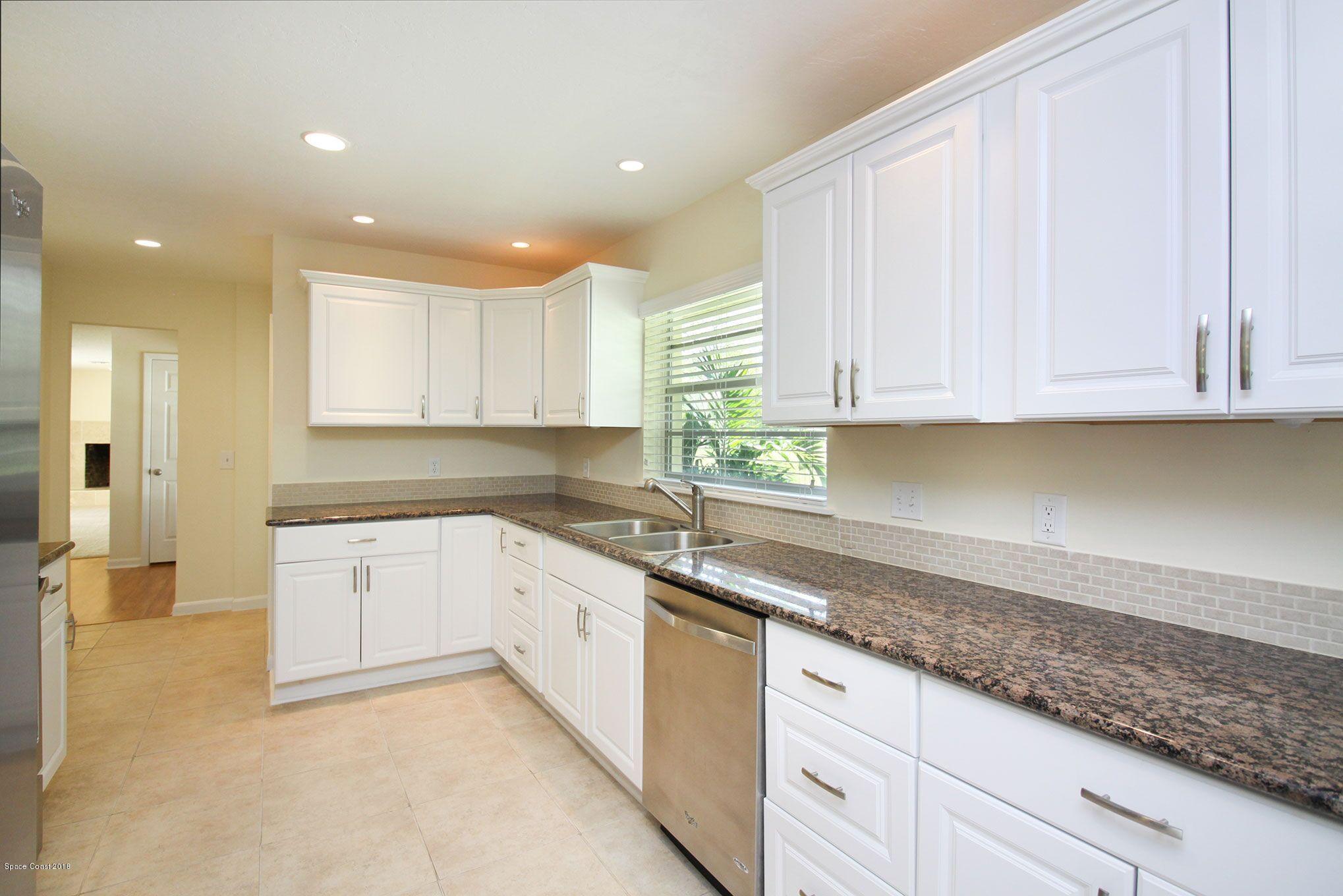 4521 Mustang Road Melbourne, FL 32934 - Photo 10 of 24 a kitchen with granite countertop white cabinets and stainless steel appliances