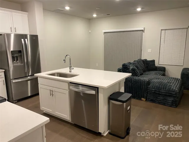 a kitchen with stainless steel appliances granite countertop a refrigerator a sink a stove and a refrigerator