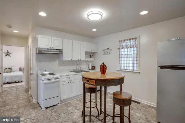 a kitchen with stainless steel appliances granite countertop a sink a stove a refrigerator cabinets and a dining table