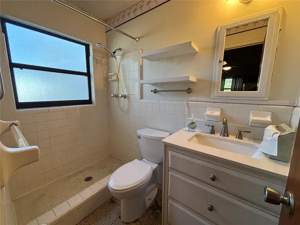 a bathroom with a granite countertop sink mirror vanity and toilet