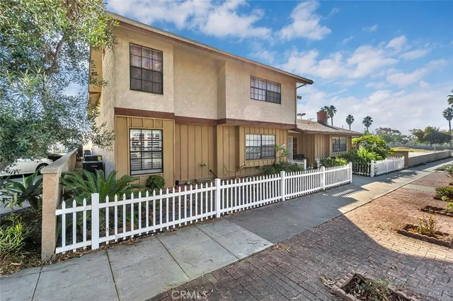 a view of a house with a small yard and wooden fence