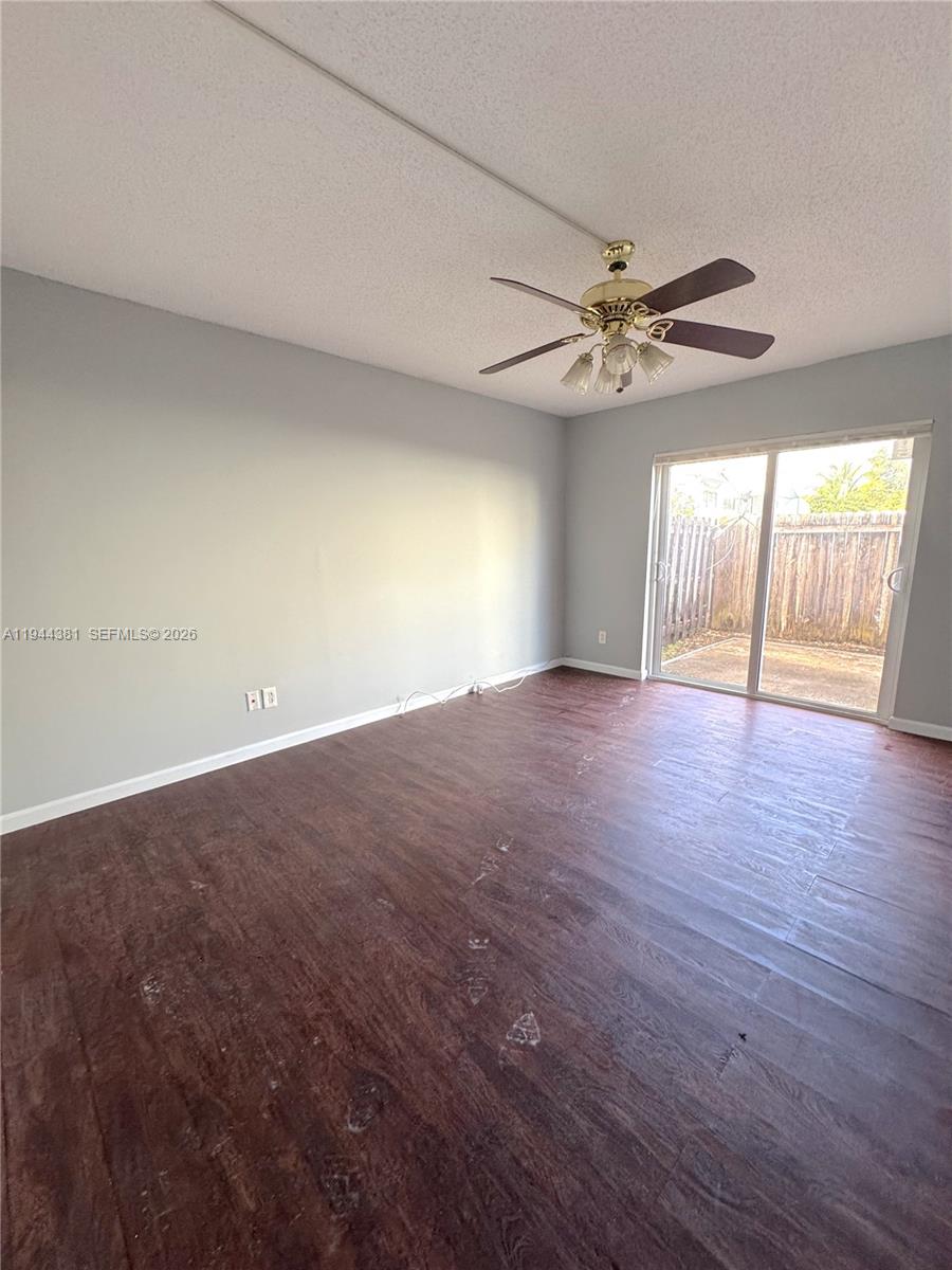 8536 Southwest 156th Court, Unit 210 Miami, FL 33193 - Photo 13 of 17 an empty room with wooden floor ceiling fan and windows