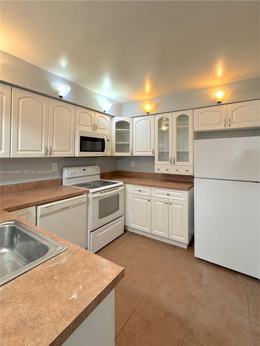 8536 Southwest 156th Court, Unit 210 Miami, FL 33193 - Photo 7 of 17 a kitchen with stainless steel appliances granite countertop a sink and white cabinets