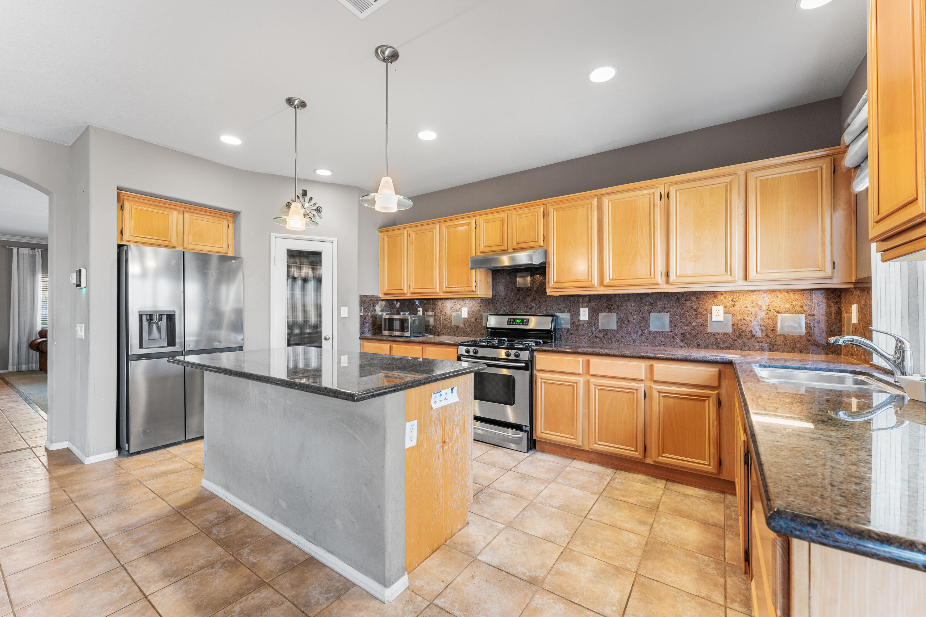 44225 Rucker Street Lancaster, CA 93535 - Photo 3 of 16 a kitchen with stainless steel appliances granite countertop a stove a sink and a refrigerator