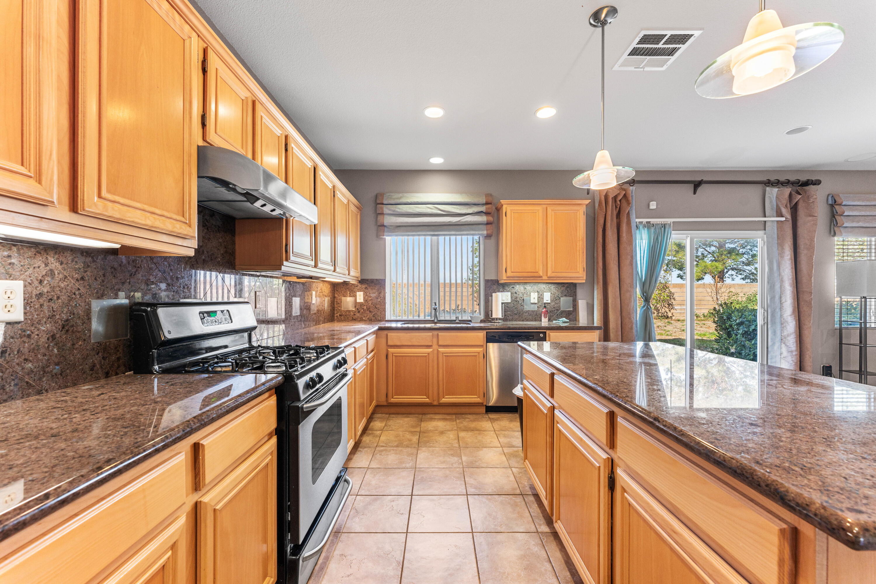 44225 Rucker Street Lancaster, CA 93535 - Photo 5 of 16 a large kitchen with stainless steel appliances granite countertop a stove and a large window