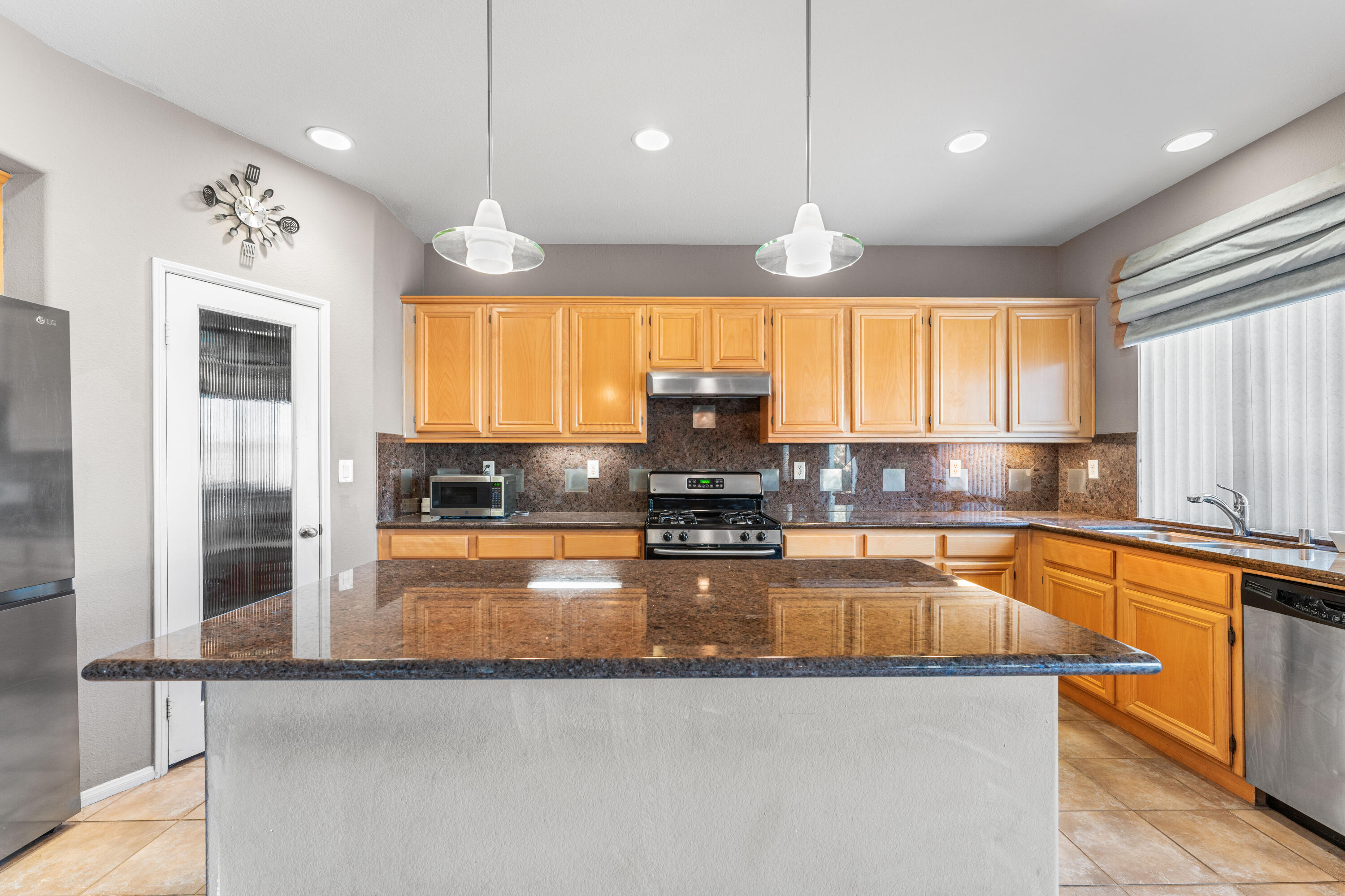 44225 Rucker Street Lancaster, CA 93535 - Photo 6 of 16 a large kitchen with granite countertop a large counter top stainless steel appliances a window and cabinets