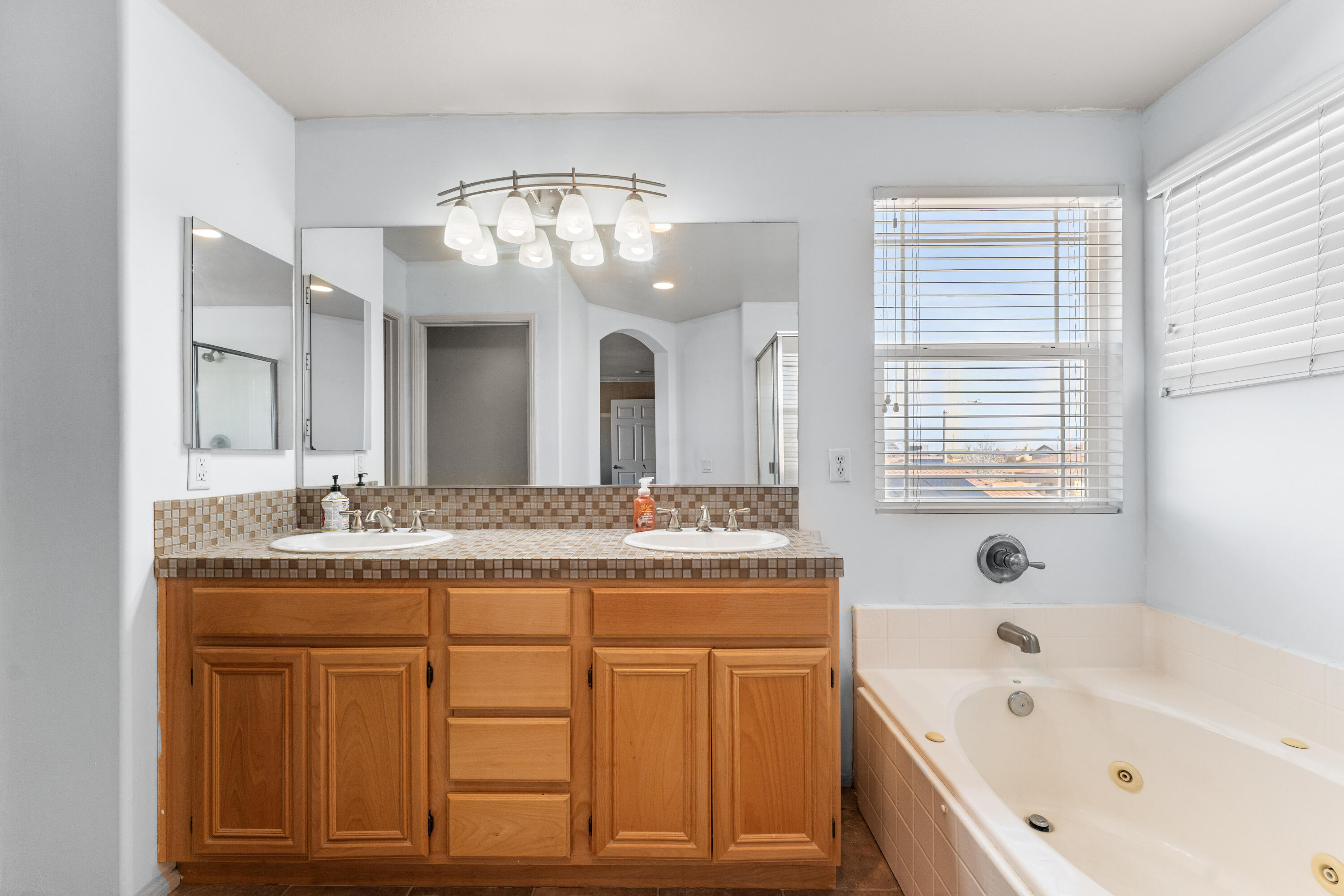 44225 Rucker Street Lancaster, CA 93535 - Photo 9 of 16 a bathroom with a granite countertop sink a large mirror and a bathtub