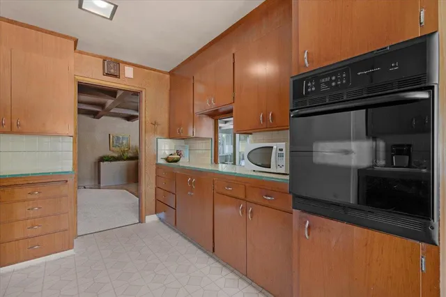 a view of a dining room with furniture a chandelier and kitchen view