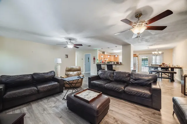 a view of a dining room and livingroom with furniture wooden floor a chandelier