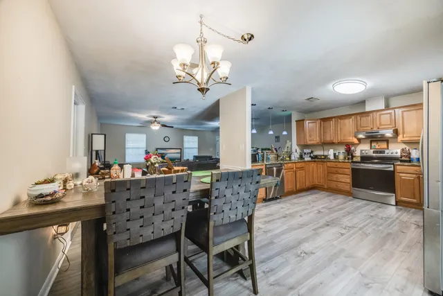 a kitchen with stainless steel appliances granite countertop wooden cabinets a sink a stove a refrigerator and microwave with wooden floor