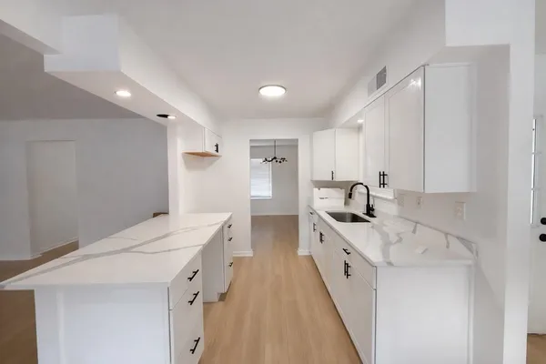 a large white kitchen with a sink a stove and a refrigerator