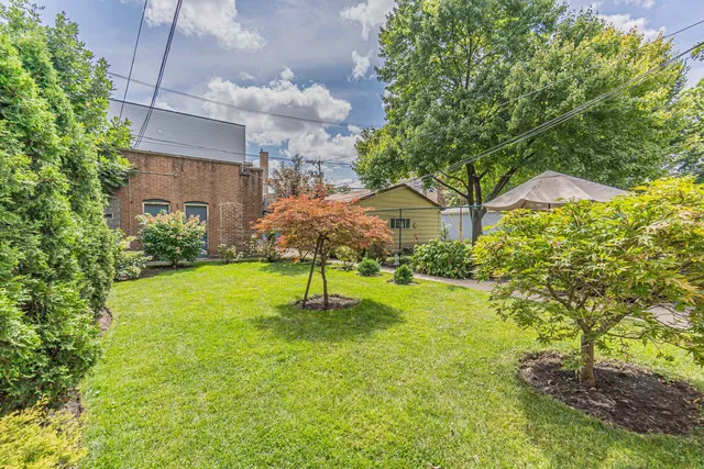 a backyard of a house with lots of plants and large trees