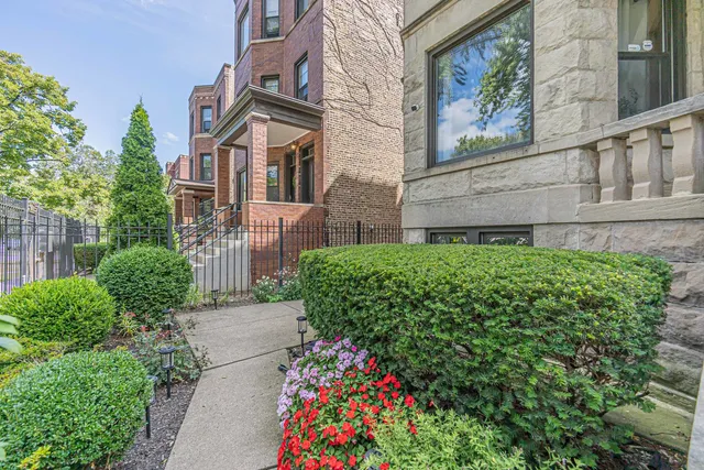 a front view of a multi story residential apartment building with yard and bench