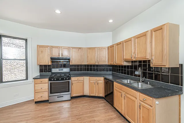 a kitchen with stainless steel appliances granite countertop a stove a sink and a microwave