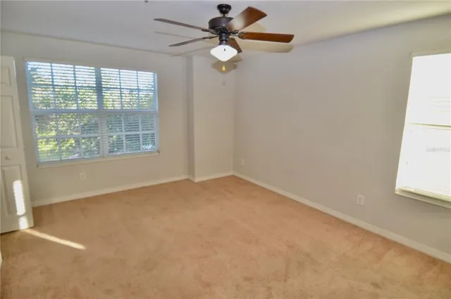 an empty room with windows and fan
