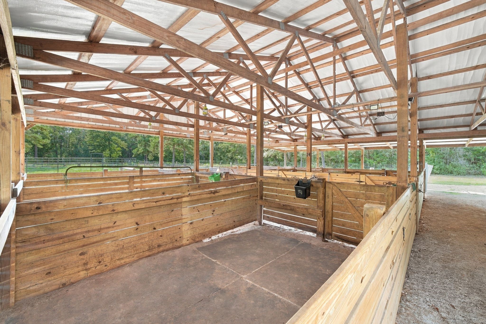 7049 Pine Shadows Road Cleveland, TX 77328 - Photo 37 of 49 Spacious horse stable with sturdy wooden stalls and an open design, perfect for equestrian enthusiasts.