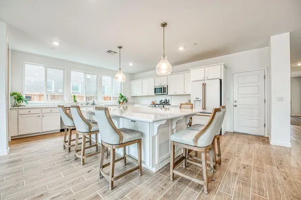 a kitchen with stainless steel appliances a dining table chairs refrigerator sink and cabinets
