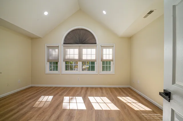 an empty room with wooden floor and windows