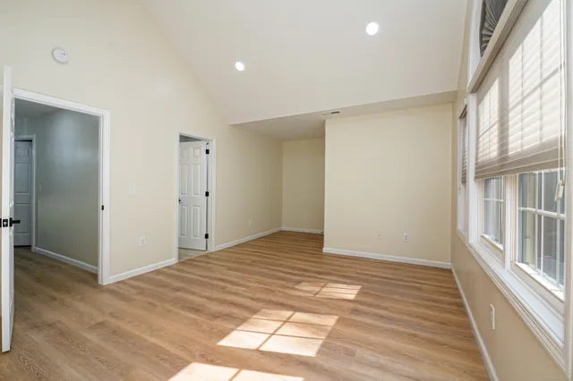 a view of an empty room with wooden floor and a window