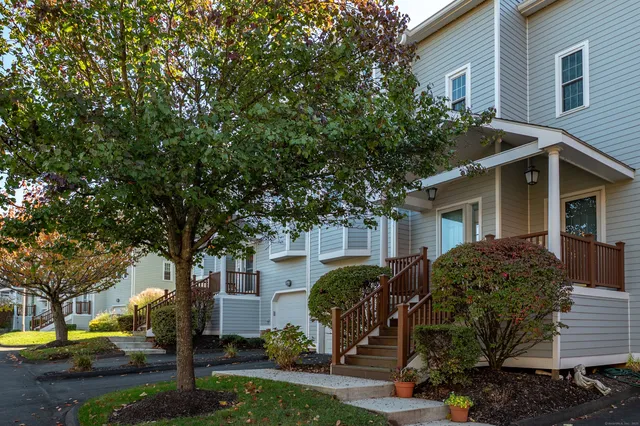 a view of a white house next to a yard with big trees