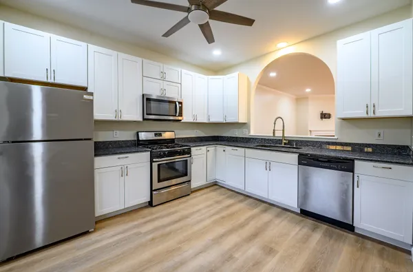 a kitchen with granite countertop a refrigerator and a stove top oven