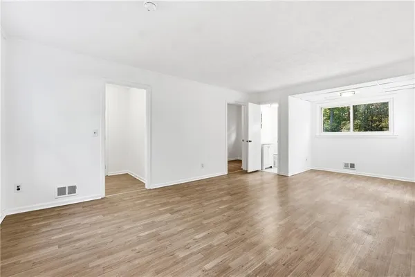 a view of an empty room with wooden floor and a window