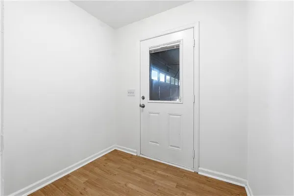a view of an empty room with wooden floor and a mirror