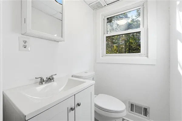 a bathroom with a sink a toilet and a window