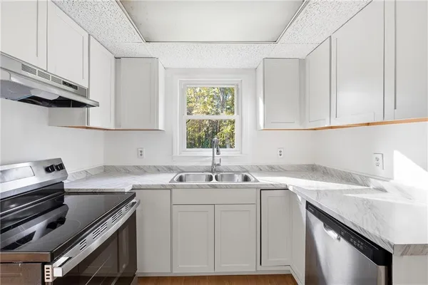 a kitchen with a sink cabinets appliances and a window
