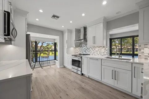 a kitchen with stainless steel appliances kitchen island granite countertop a stove a sink and white cabinets with wooden floor